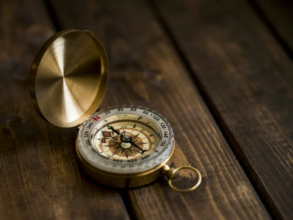 A brass compass resting on a wooden table